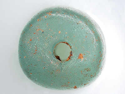 A blue-green glass bead with a hole in the middle